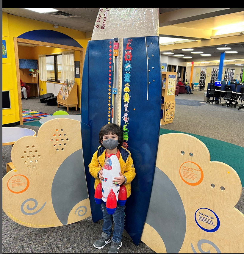 Child at Johnson County Library children's area with rocket