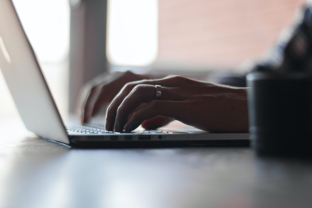 Hands typing on a laptop computer